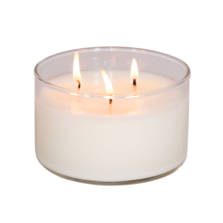 Three-wick candle in a clear glass container on a white background